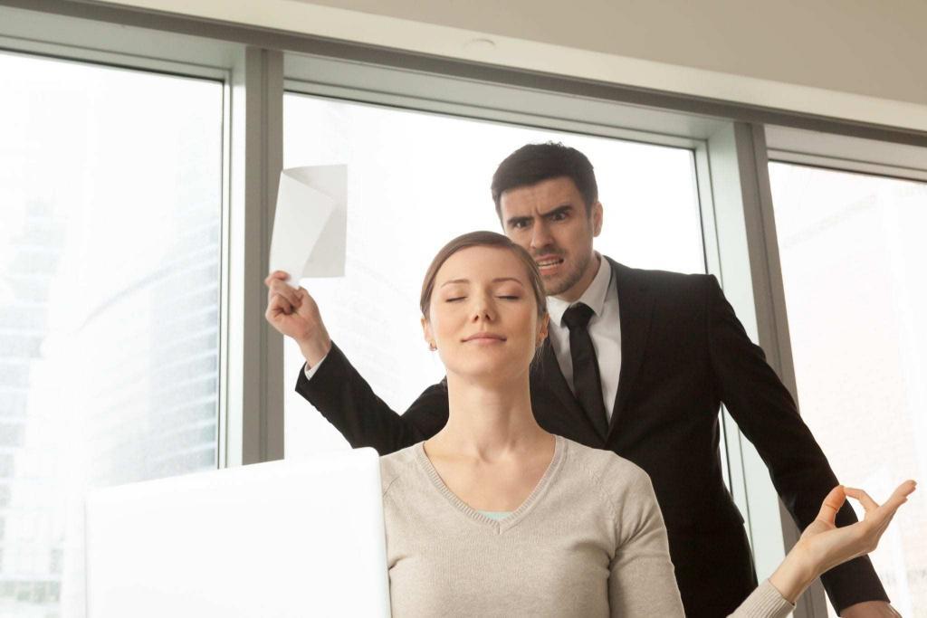 Woman sitting at a desk looking zen and relaxed while the boss is shouting behind her, 7 ways to master stress, e-Surgery