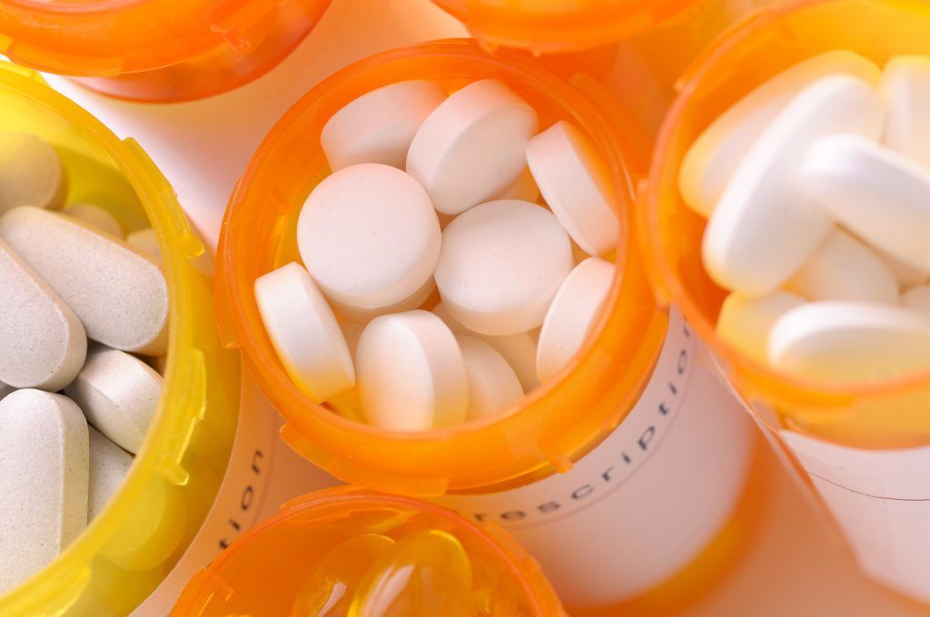 Orange pots of pills. The pills in the centre of the image are white and circular. To the left and right of the central pot, the pills re oval and white. | Obesity: What You Need To Know | e-Surgery 