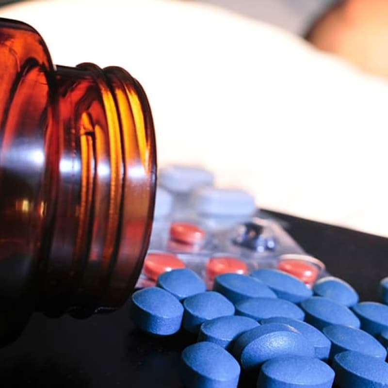 Man sleeping with blue tablets on his bedside cabinet, erectile dysfunction | e-Surgery