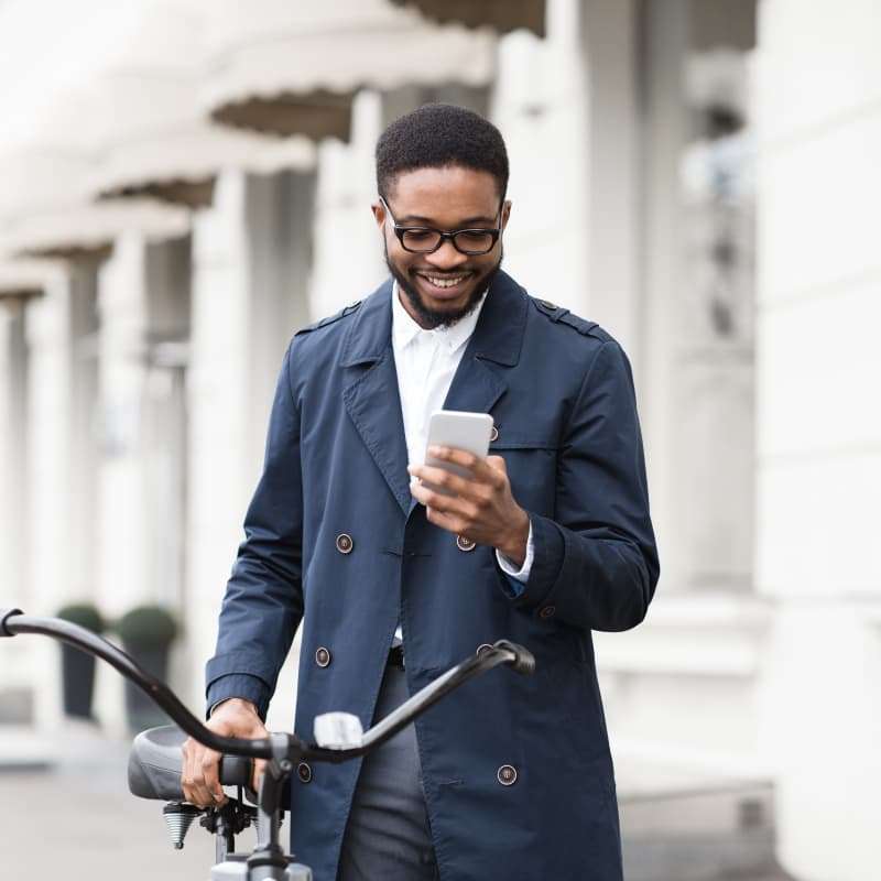 young man on his phone holding his bike in his hand | e-Surgery