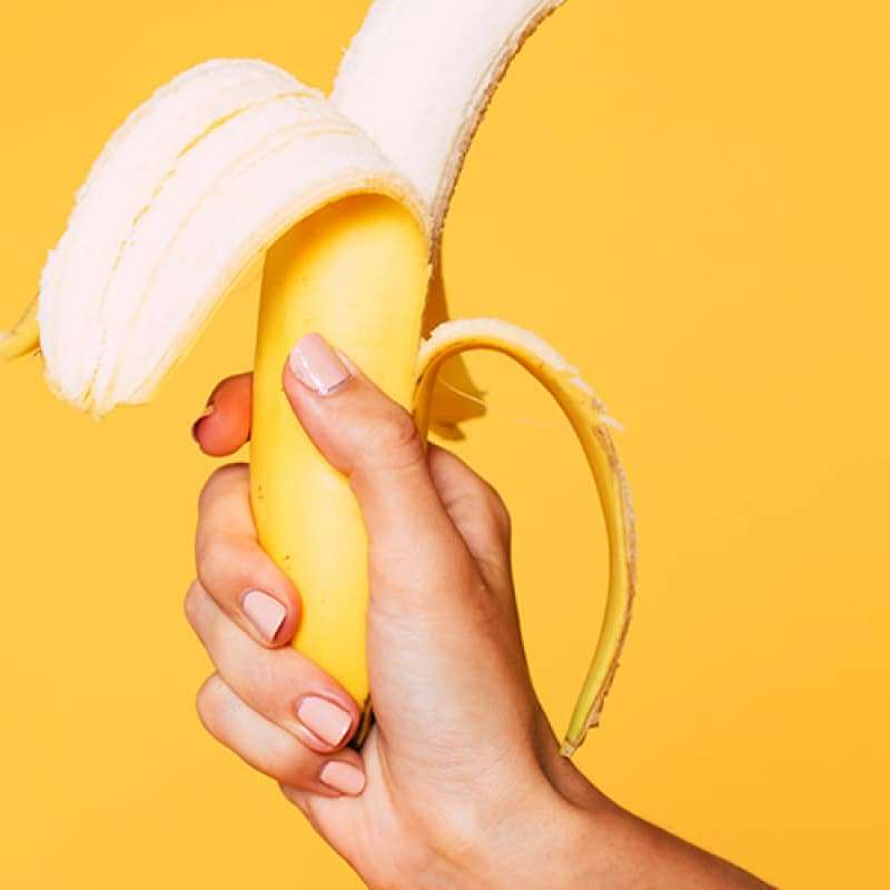 Person holding a banana that has been peeled at the tip | e-Surgery