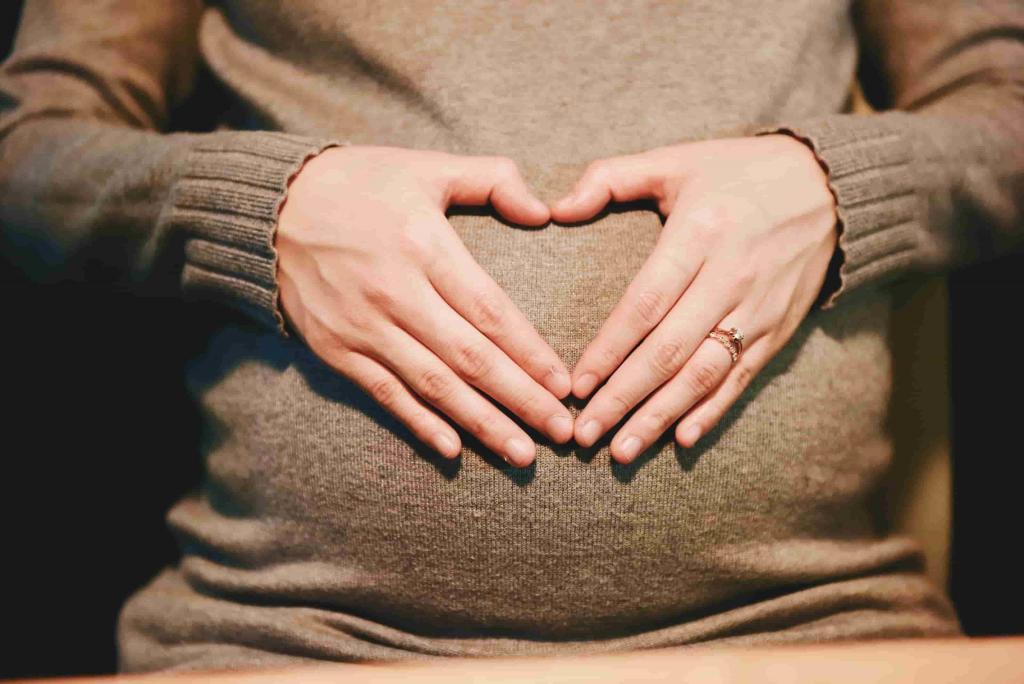 Woman holding hands in shape of heart over baby bump