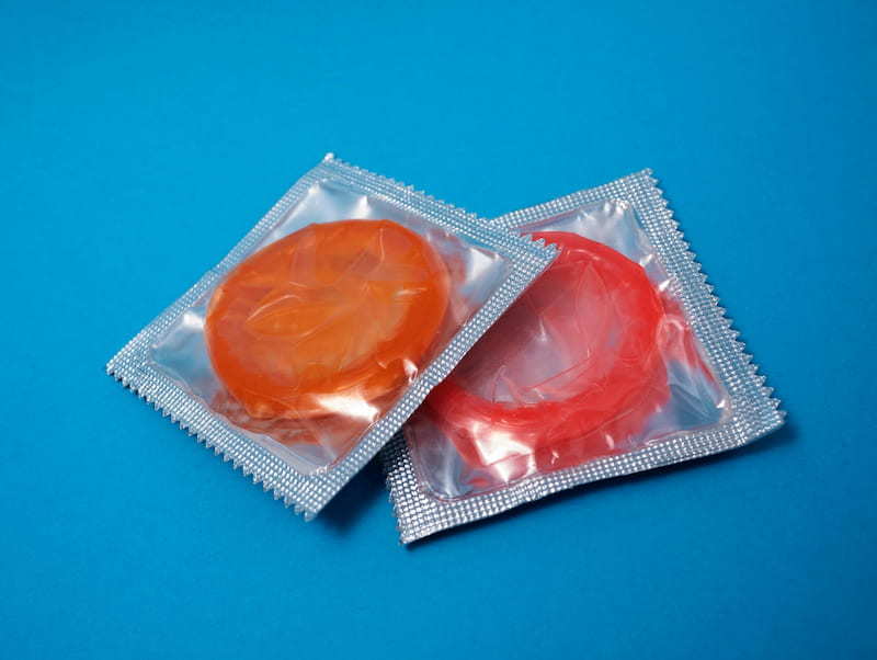 Two condoms in their packaging. One is orange in colour the other red | The (almost) A-Z of Contraception | e-Surgery 