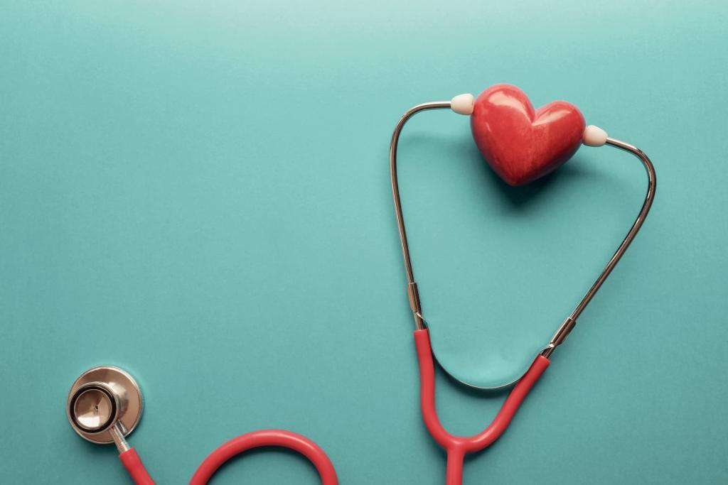 Red stethoscope with a marble red heart between the ear pieces resting on a green surface.  This image indicates a healthy heat that could be achieved with use of statins to treat high cholesterol | Statin Side Effects: Should You Be Scared? | e-Surgery 