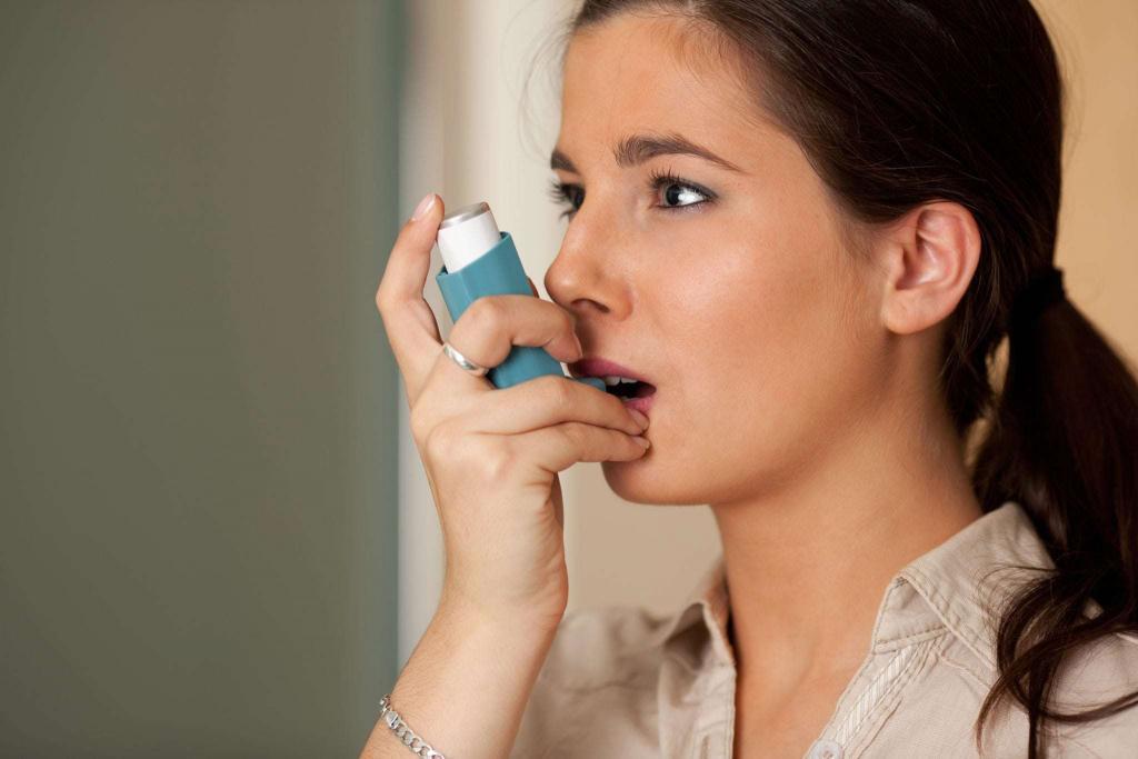 Woman using blue inhaler for asthma, the importance of cleaning your asthma inhaler, e-Surgery