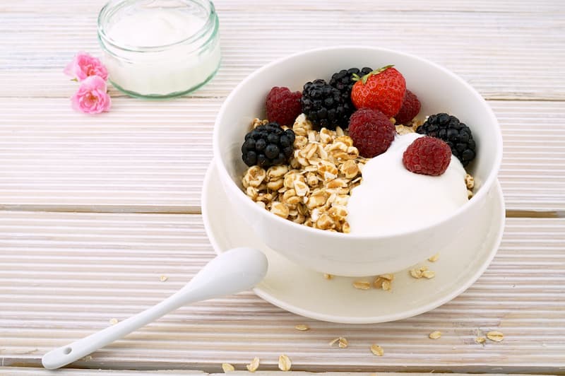 Bowl of granola and fruit on a wooden table  | Trust Your Gut: Can Healthy Bacteria Make You Happy?  | e-Surgery 