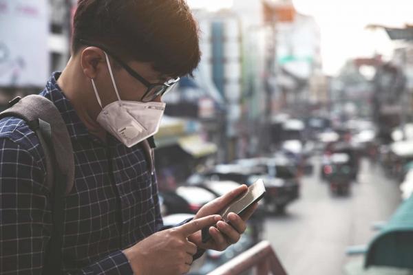 Man using mobile phone wearing PPE face mask, e-Surgery