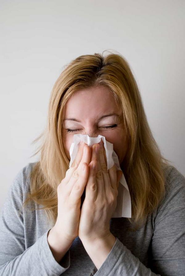 Blond woman blowing nose suffering from a cold, e-Surgery