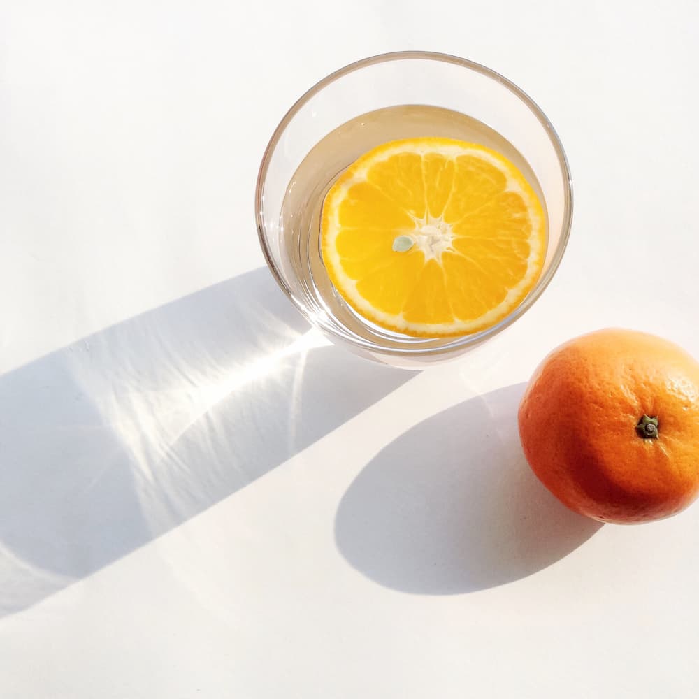 Cup of water with slice of orange, hydration can help with acne in lockdown, e-Surgery