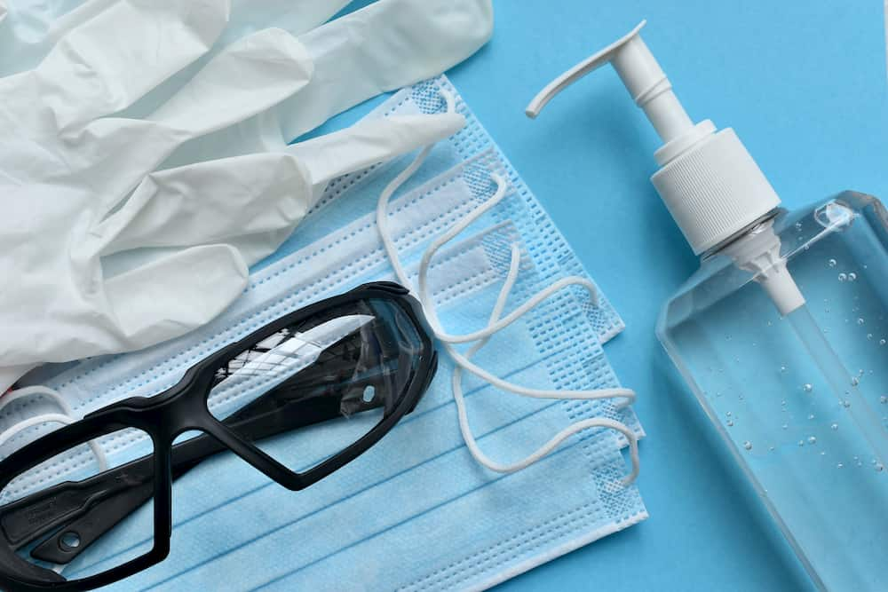 Hand sanitiser, gloves and masks on blue table, e-Surgery