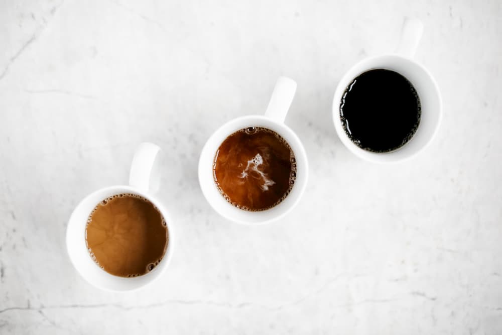 Three cups of coffee varying in strength sitting on a marble counter top | Try These Simple Home Remedies For Acid Reflux & Heartburn | e-Surgery 