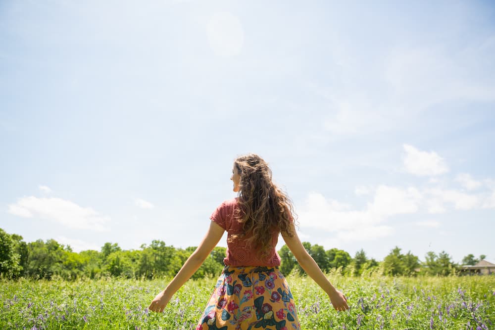 Woman in floral skirt standing in a summer field, are sunblock pills safe? e-Surgery