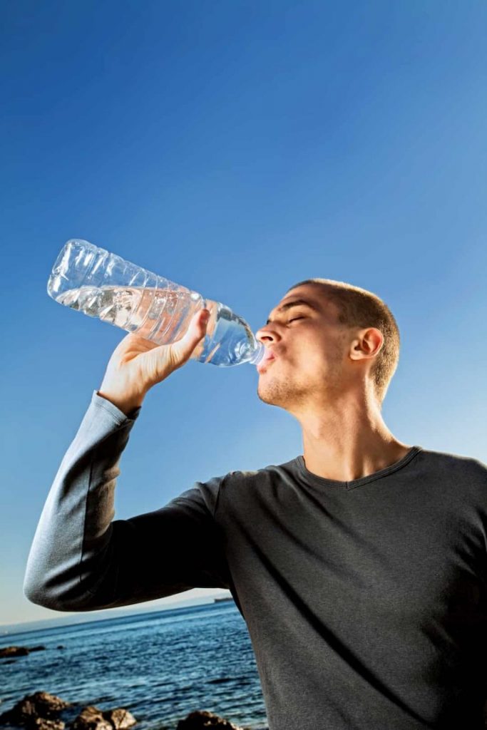 Man drinking bottle of water, tips to stay hydrated, e-Surgery