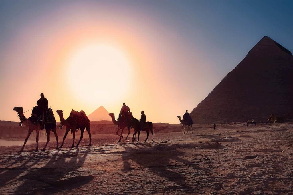 A sun is setting in a desert, there is a pyramid is in the background and six people are riding camels along a desert path | Period-tech: 5 Ways Technology is Changing Women’s Health | e-Surgery 