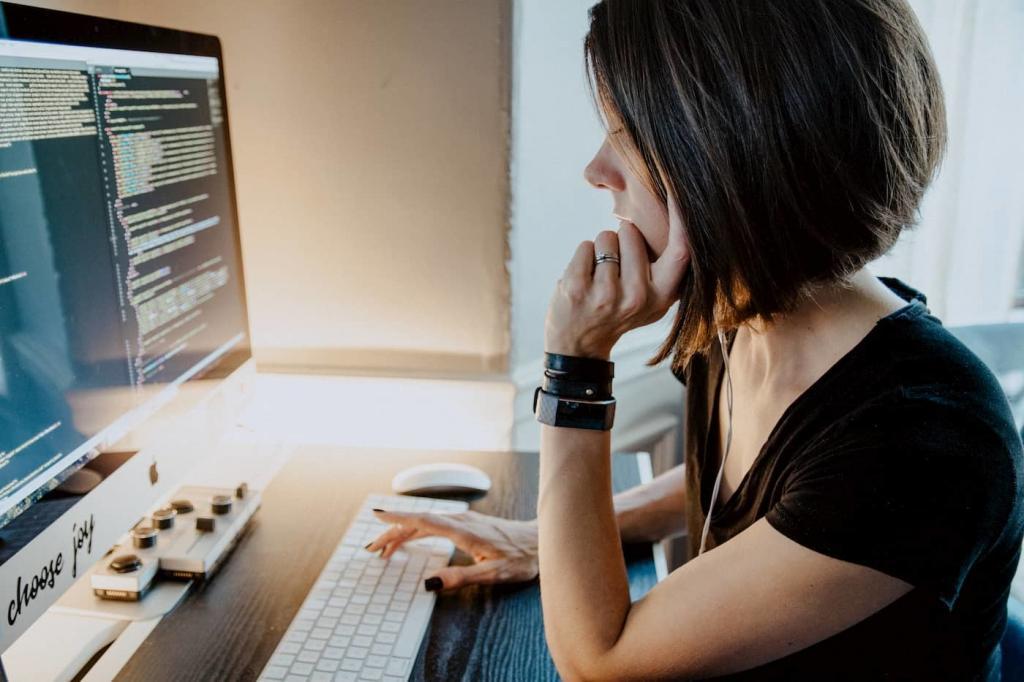 Young female with short hair sitting at a desk resting her chin on her hand and typing on a keyboard with her other. Her computer screen is filled with code  | Period-tech: 5 Ways Technology is Changing Women’s Health | e-Surgery 