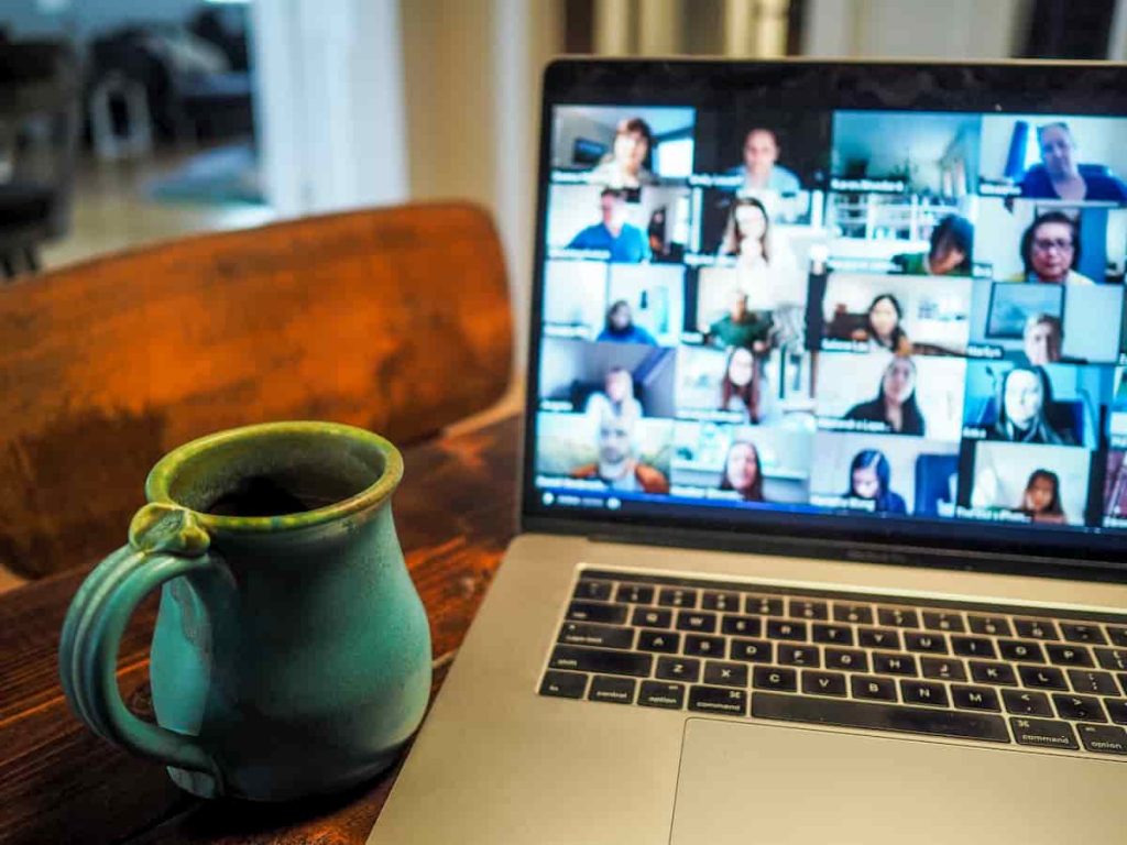 Group video call on laptop with mug on table next to it