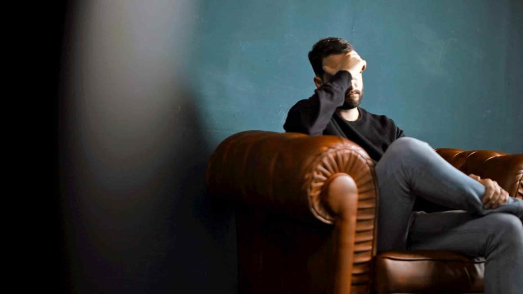 Man with migraine sitting on sofa