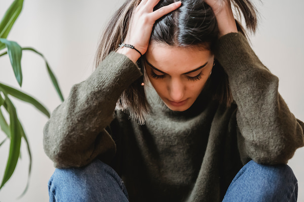 Woman holding head in pain from migraine and high blood pressure