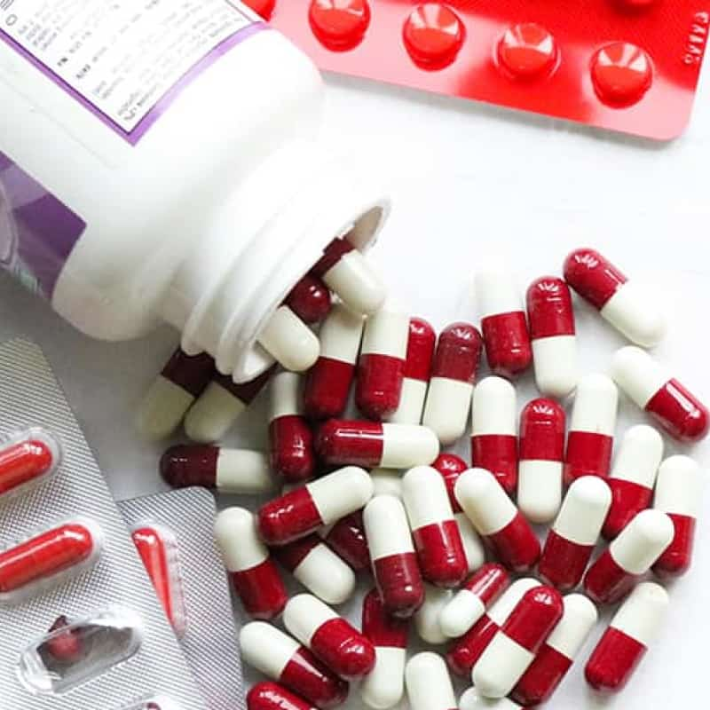 pot of red and white pills spilled onto a table. Is my medication vegan? | e-Surgery