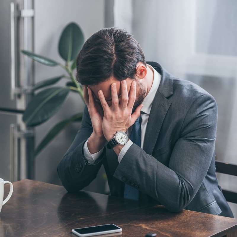 business man holding his head in his hands. Male burn out | e-Surgery