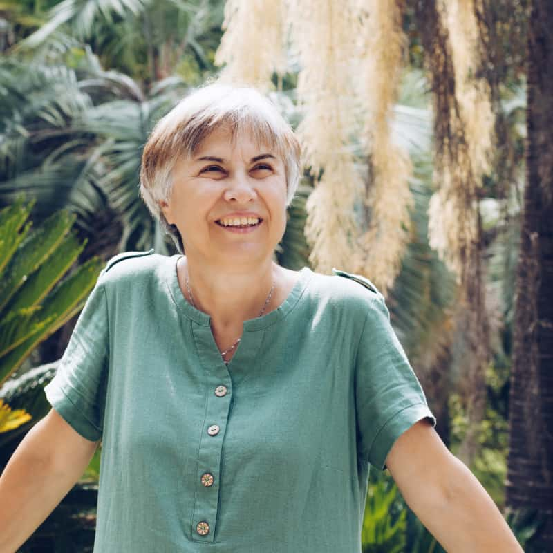 elderly woman in a green shirt smiling outside. HRT side effects and results for menopause | e-Surgery