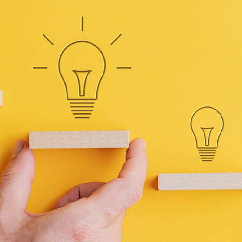 Our next step to a sustainable future, light bulbs drawn on a yellow background with small wooden shelves below them | e-Surgery