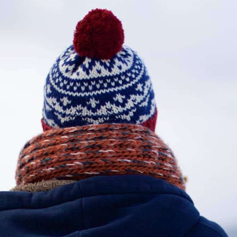 Stay healthy this winter, person facing away from the camera looking out over a snowy scene wearing a navy coat, a hat and scarf | e-Surgery